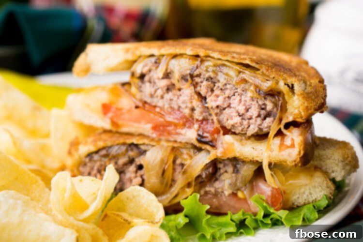 The Ultimate Patty Melt 3 Close-up of a halved Classic Patty Melt showcasing the juicy patty, melted Swiss cheese, and rich caramelized onions inside.