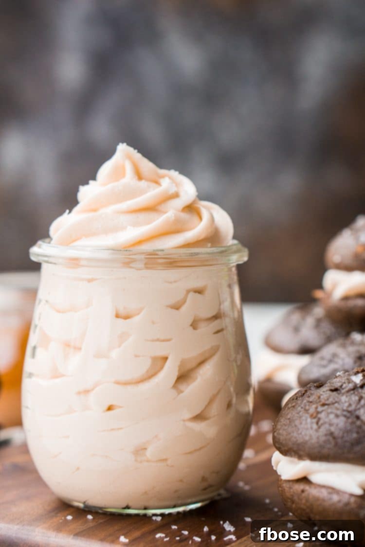 A beautifully decorated cupcake, topped with a swirl of Salted Caramel Frosting and a sprinkle of sea salt.