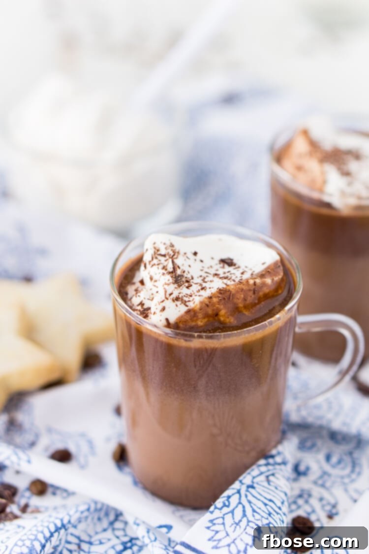 A close-up of a mug of Hot Chocolate Coffee, topped with whipped cream and chocolate shavings.