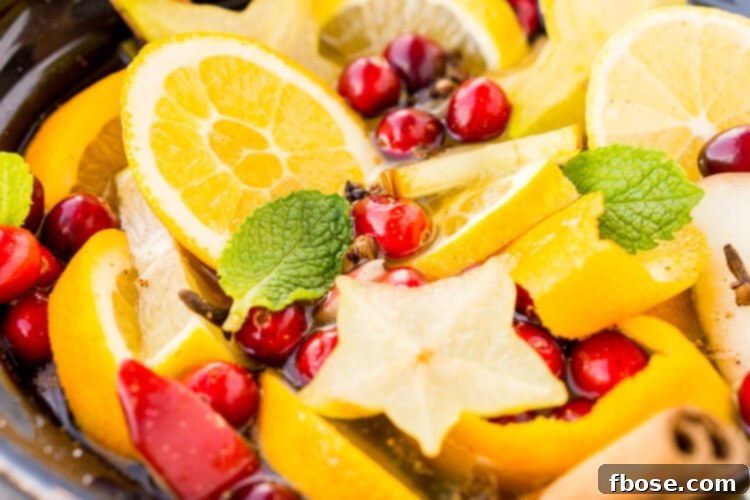 A festive DIY Holiday Crock Pot Potpourri simmering with cranberries, oranges, mint, cloves, and cinnamon to make your home smell amazing for the holidays.