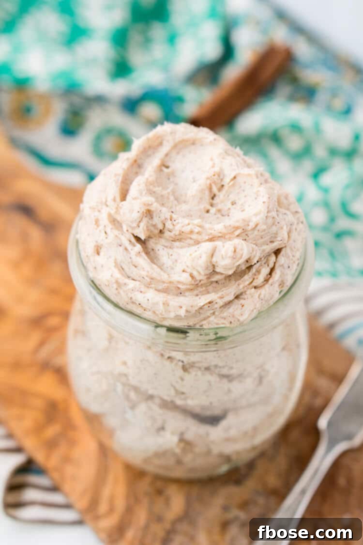 Freshly churned homemade cinnamon butter in a small white bowl, ready for spreading. It's creamy, light brown, and speckled with cinnamon, making it perfect for dinner rolls or toast.