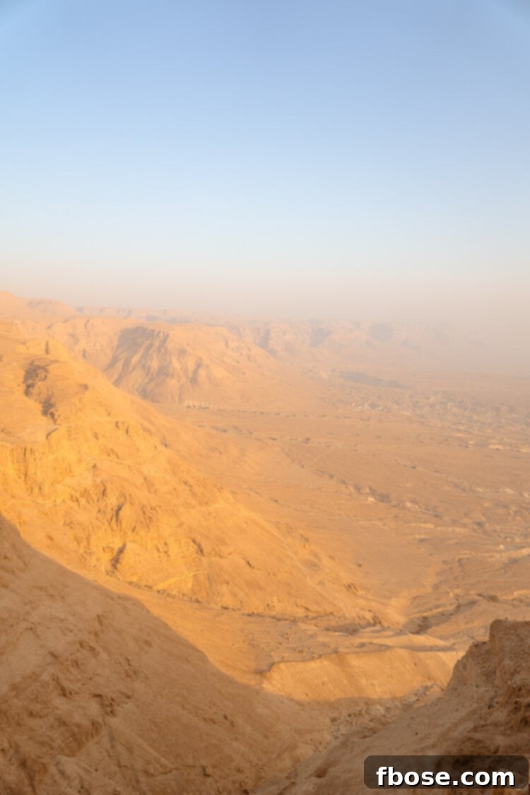 A person silhouetted against the vibrant sunrise at Masada, contemplating the view