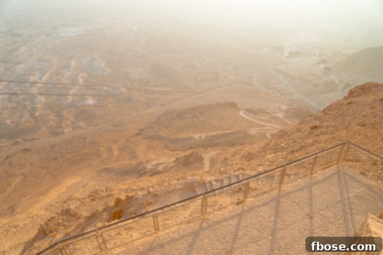 A lone hiker on the Masada Snake Path, with the vast desert stretching behind them