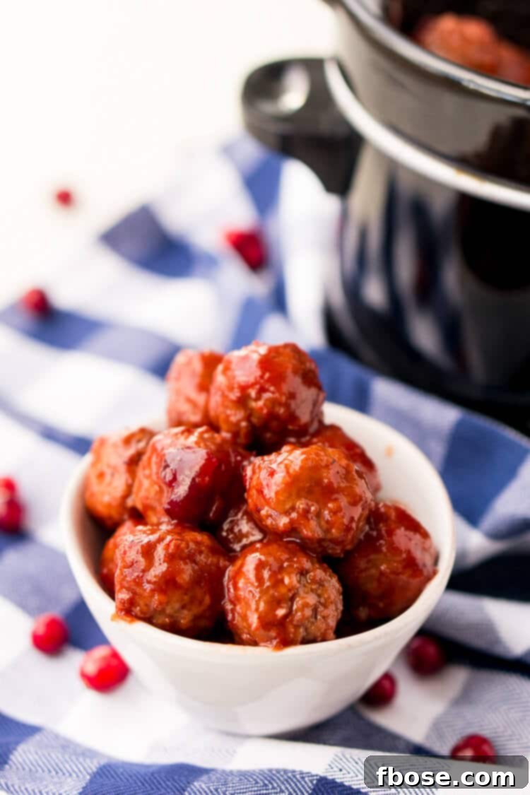 Close-up of Cranberry Orange Meatballs simmering in a slow cooker, highlighting the rich sauce and tender texture. An easy, delicious appetizer for any occasion.