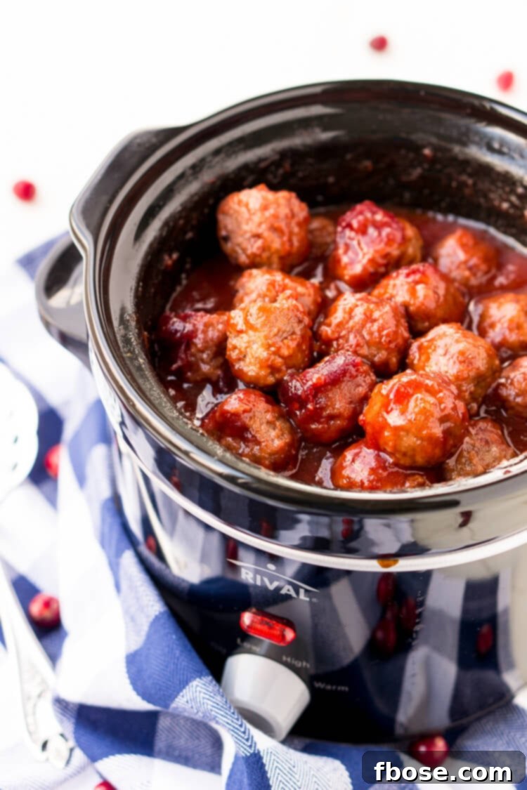 A festive spread of Cranberry Orange Meatballs in a slow cooker, garnished with fresh herbs and orange slices, ready for a party.
