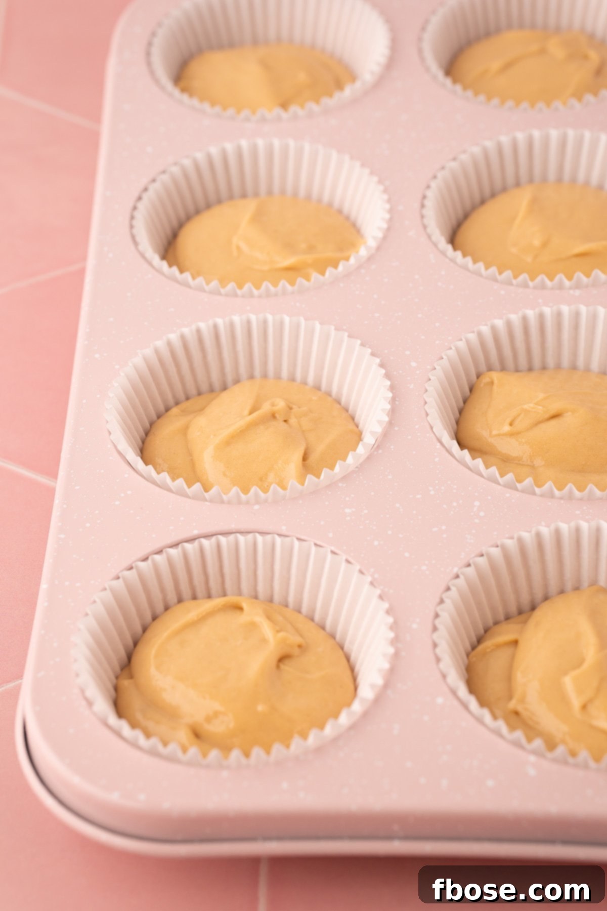 Cupcake batter in liners in a pan ready to bake.
