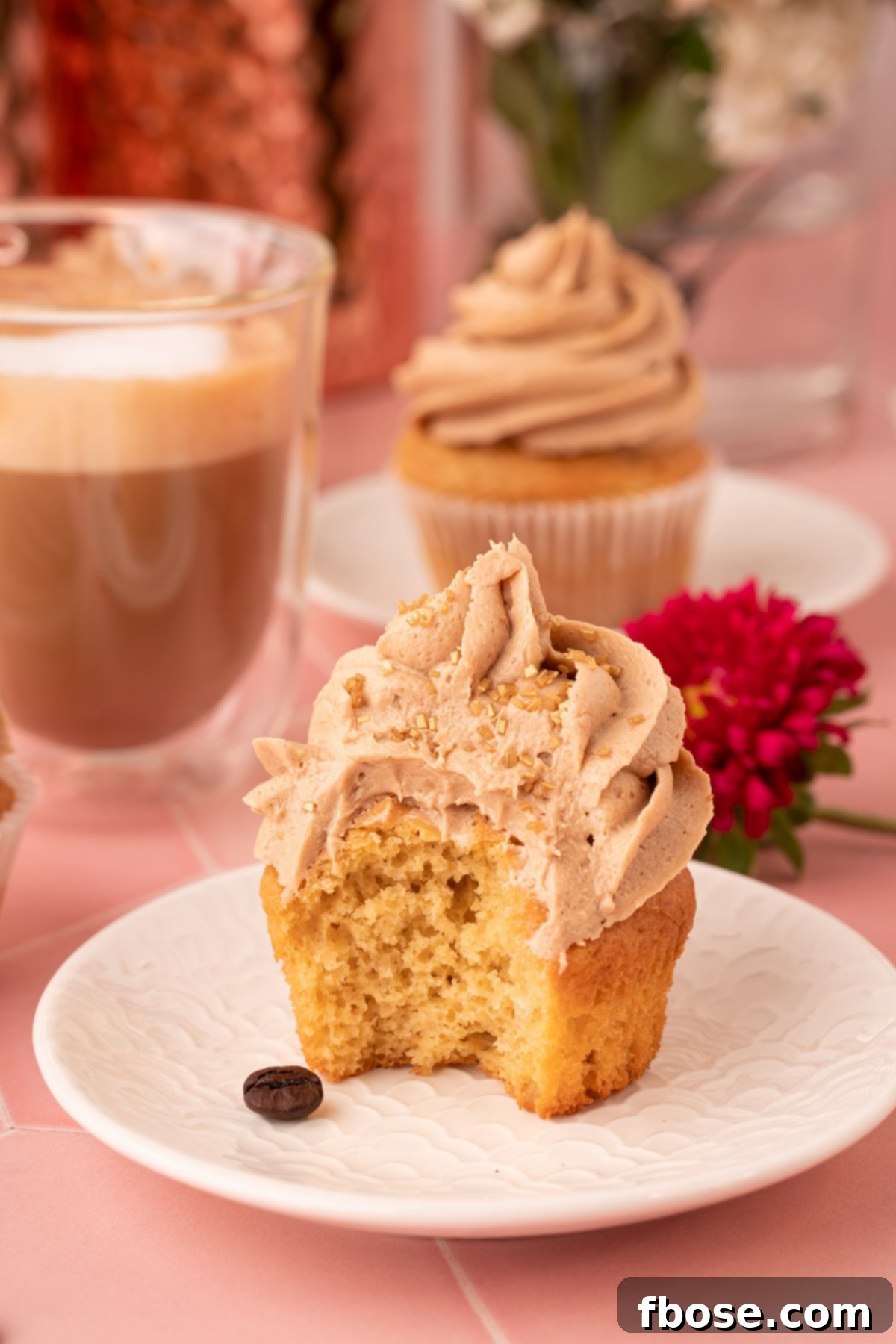 A French Vanilla Cupcake on a white plate with a bite missing.