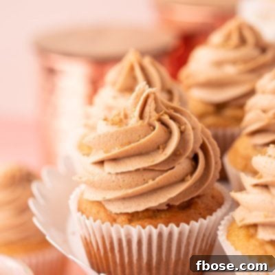 Close up photo of a french vanilla cupcake on a white cake stand with other cupcakes.