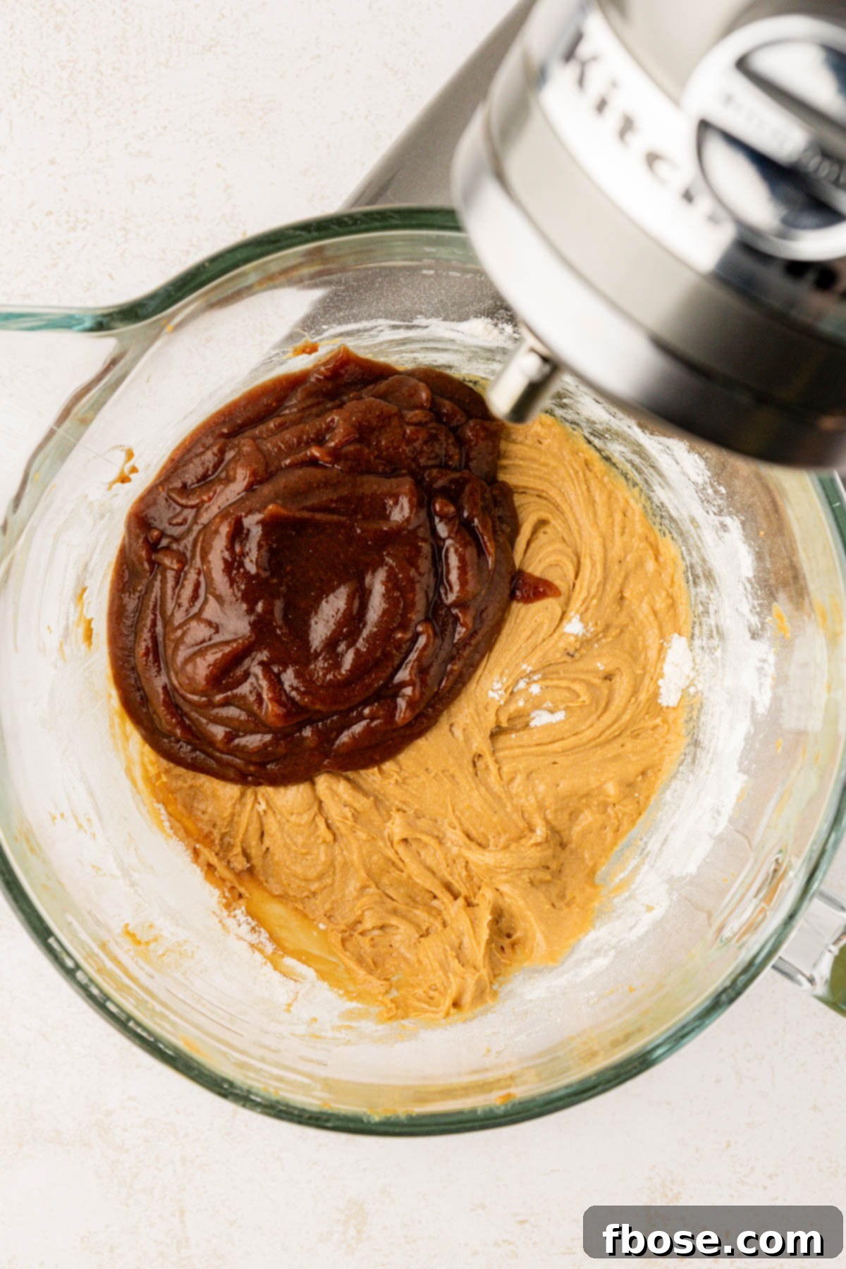 Date puree being added to batter in a glass mixing bowl.