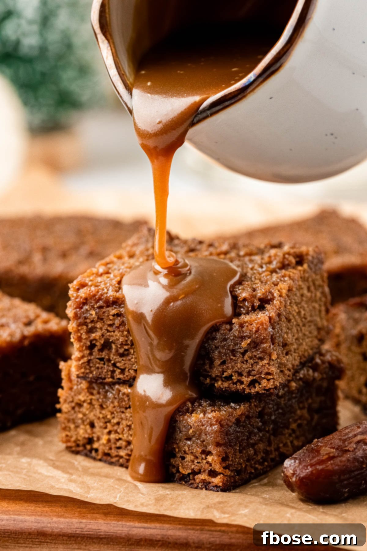 Toffee sauce being poured over sticky toffee pudding.