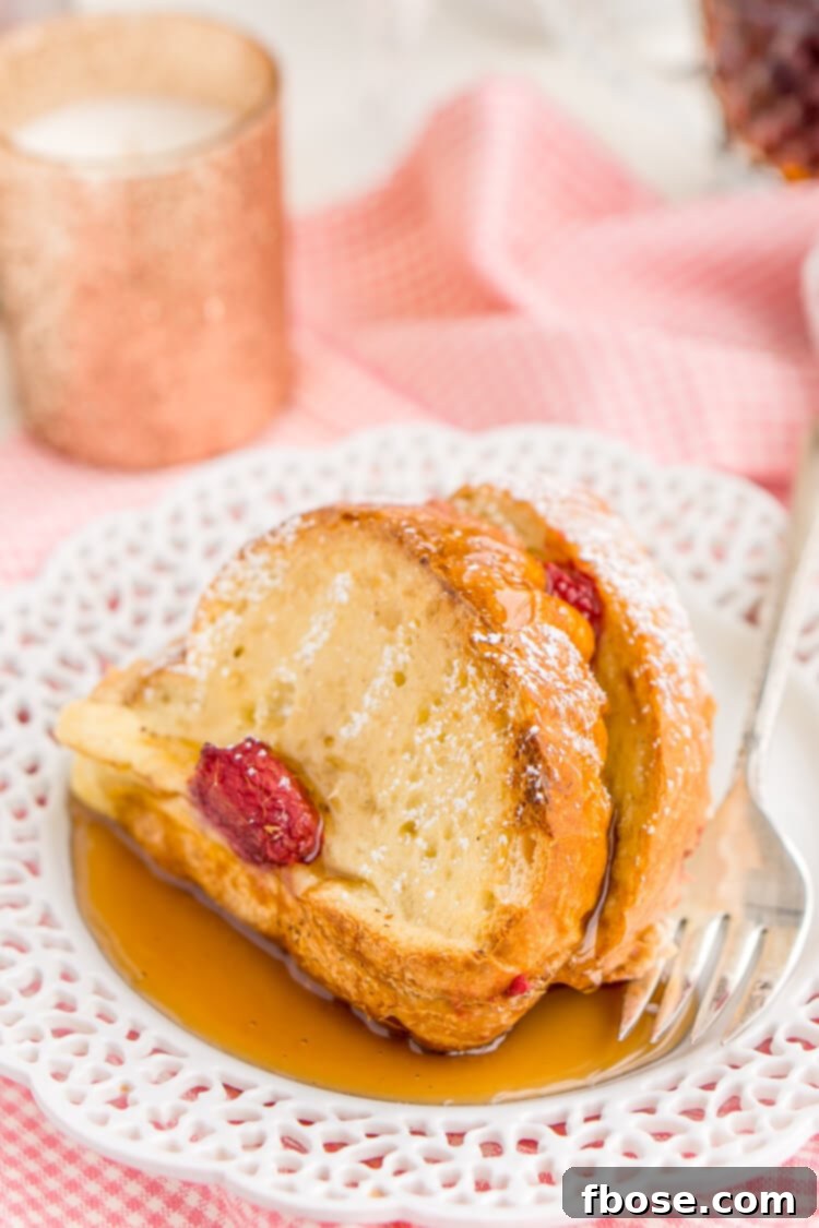 Champagne Raspberry Baked French Toast garnished with a sprig of mint and fresh raspberries, highlighting its festive and inviting appeal.