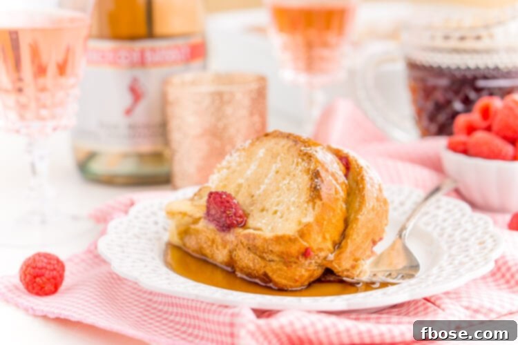 Overnight Champagne Raspberry Baked French Toast casserole baked to perfection, garnished with fresh berries, ideal for a festive brunch.