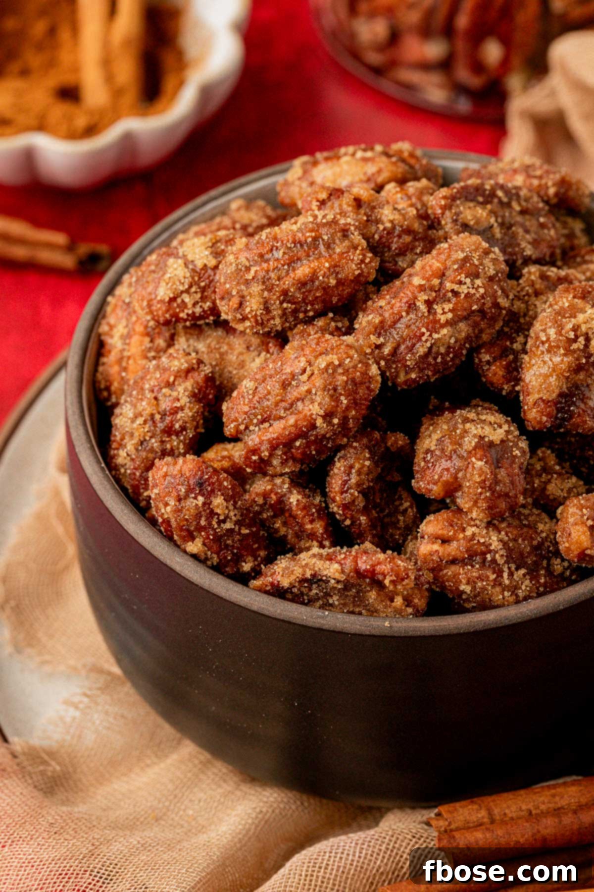 A elegant black bowl generously filled with a heap of shiny, delicious candied pecans, perfect for serving.