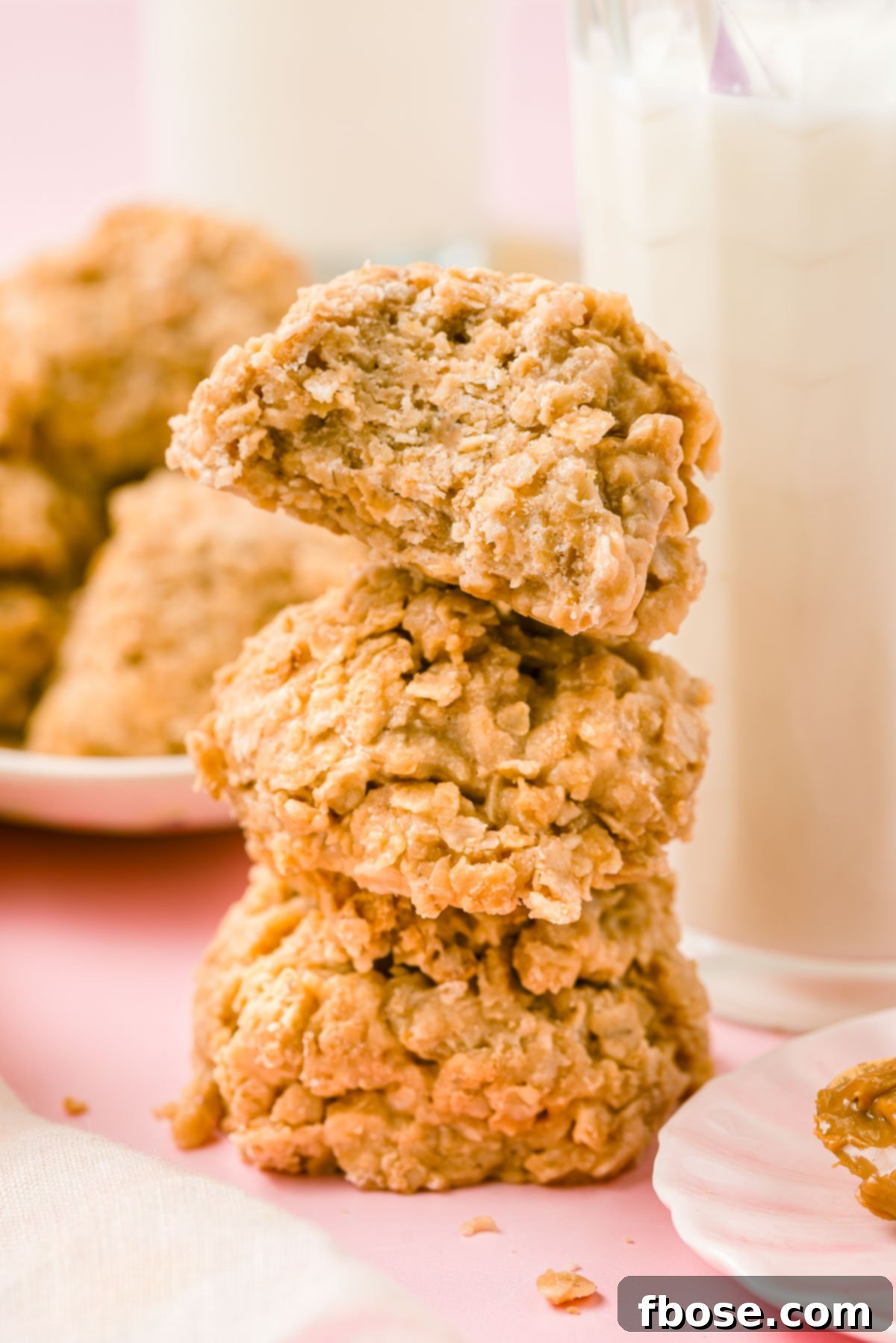 Three golden brown Cookie Butter No Bake Cookies stacked next to a glass of milk, invitingly placed on a rustic surface.