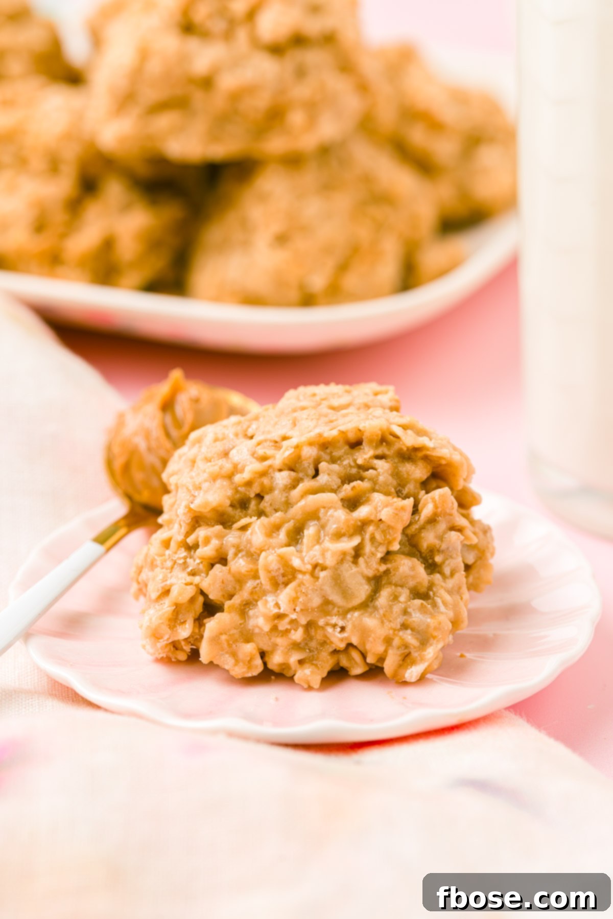 A single Biscoff cookie butter no bake cookie rests on a pink plate, accompanied by a small spoon holding a dollop of creamy cookie butter.