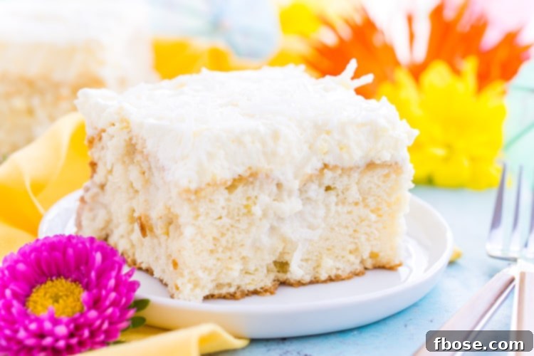 A close-up of the creamy, fluffy frosting being spread evenly over the coconut-soaked cake.