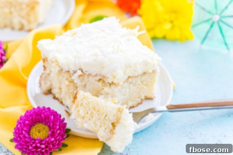 Overhead shot of the finished Coconut Poke Cake in a baking dish, perfectly frosted and covered with shredded coconut.