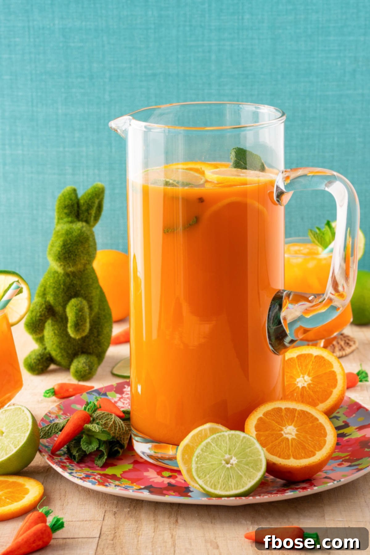 A beautiful pitcher brimming with orange and carrot Easter punch, artfully arranged on a table with fresh citrus slices and decorative elements for a spring celebration.