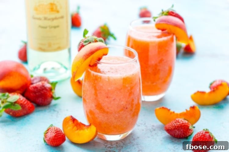 Close-up of two Strawberry Peach Wine Slushies, showing the frosty texture and colorful fruit.