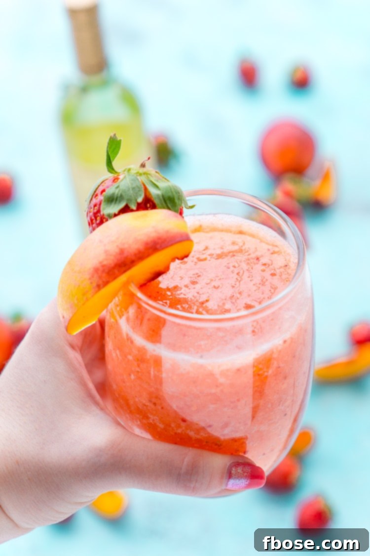 Two hands clinking stemless wine glasses filled with Strawberry Peach Wine Slushies.