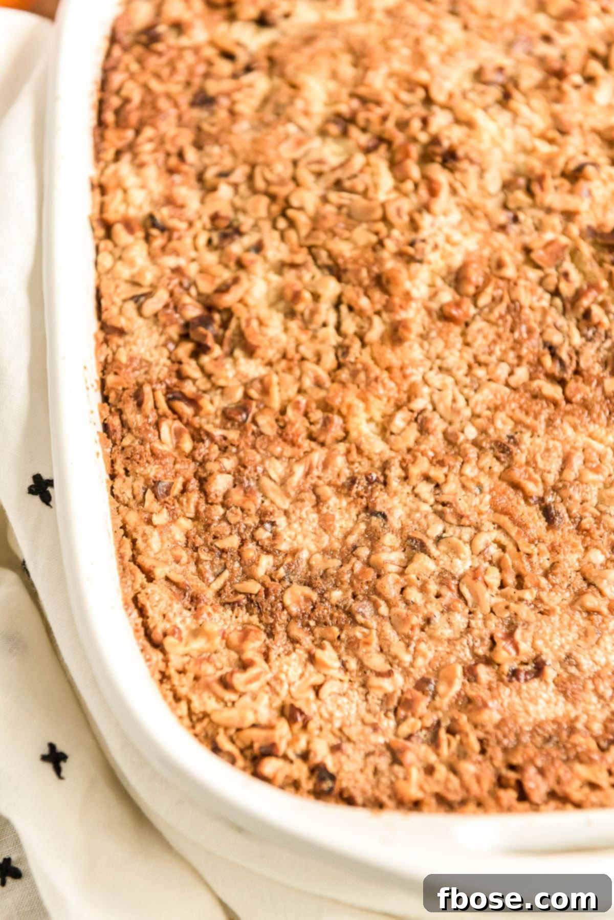 Close up photo of pumpkin cake topped with nuts still in the baking dish.