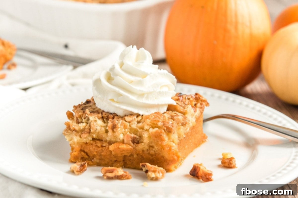 photo of a slice of pumpkin crunch cake on a white plate with pumpkins in the background.