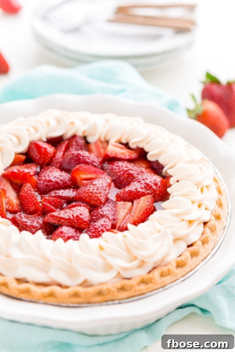 Pink Cloud Strawberry Pie 2 A vibrant slice of fresh Strawberry Jello Pie with a golden crust and a glistening red strawberry filling, topped with a dollop of whipped cream.