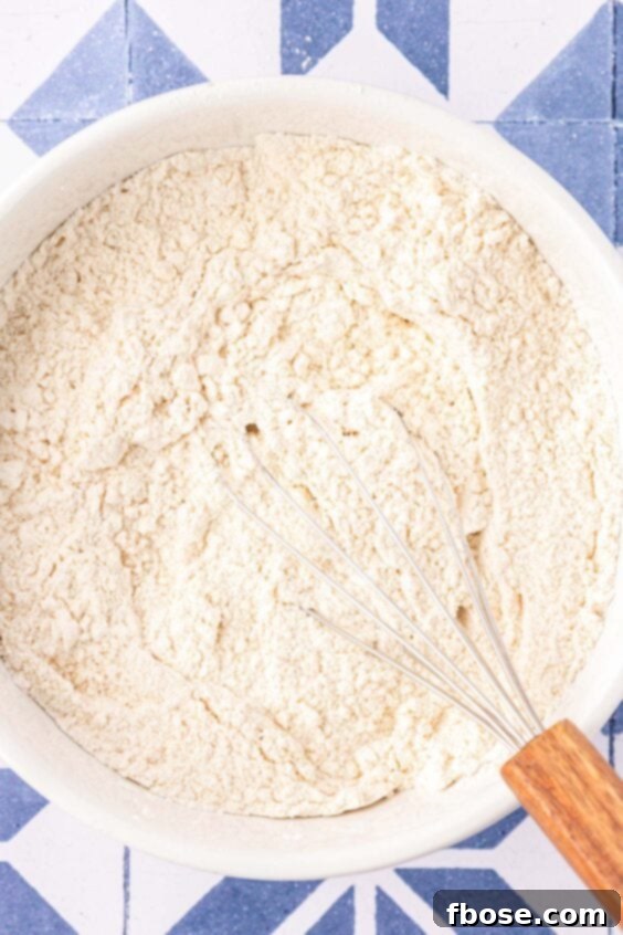 Dry ingredients being whisked in a mixing bowl for chocolate chip cookies.
