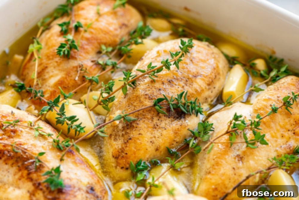 Close up photo of chicken breasts, garlic, thyme, and olive oil in a baking dish.