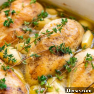 Close up photo of chicken breasts, garlic, thyme, and olive oil in a baking dish.