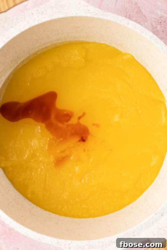 Vanilla being added to melted butter and sugar in a pot.