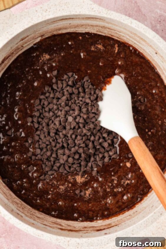 Chocolate chips being folded into brownie batter.