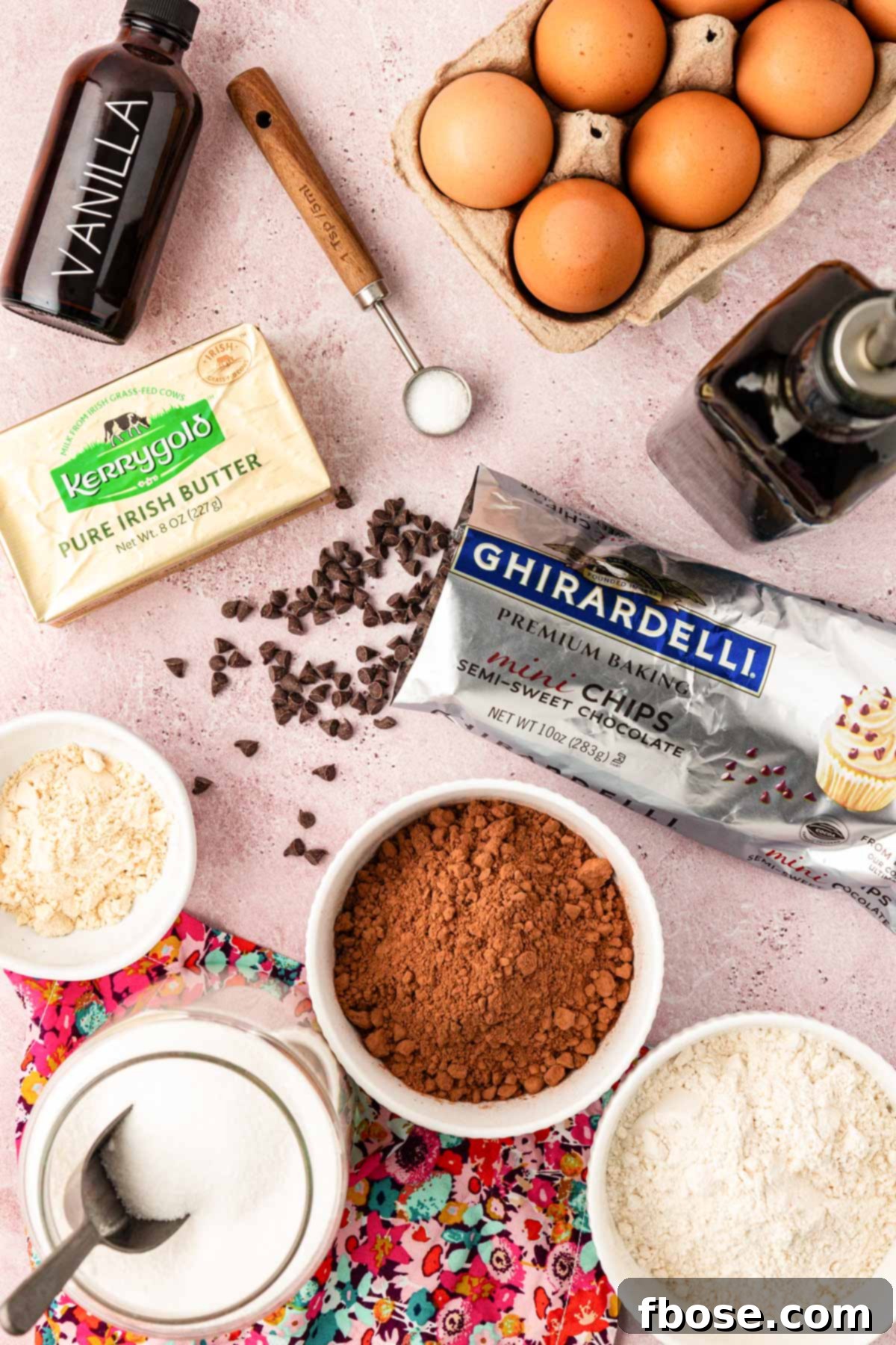 Various ingredients for fudge brownies laid out on a table, including butter, sugar, eggs, flour, and cocoa powder.