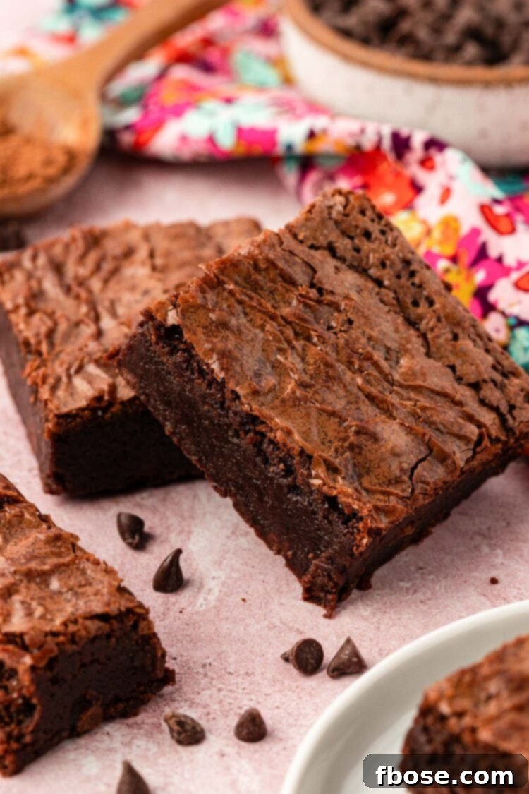 Close up photo of brownie squares on a pink surface, showing thinner slices.
