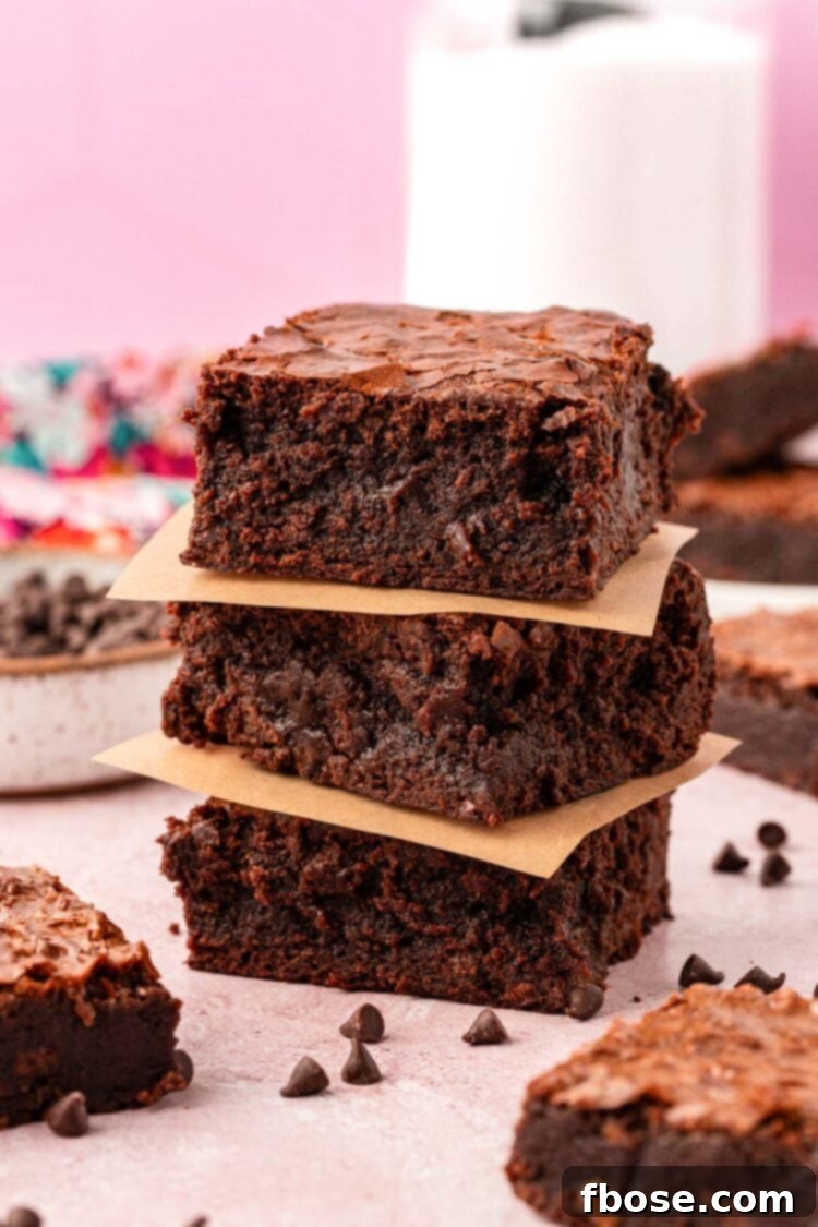 A stack of three thick brownies on a table, highlighting their substantial size.