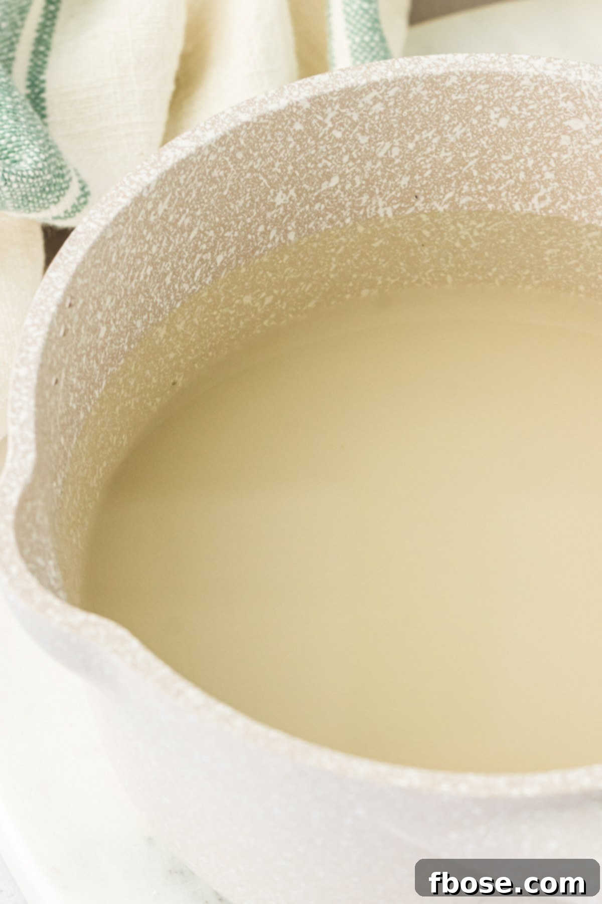Sugar and water combined in a pot, ready to be heated to make simple syrup.