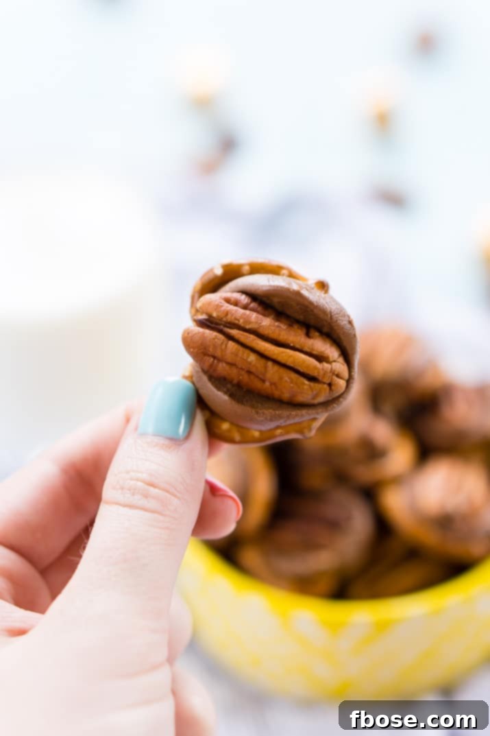 Close-up of a Pretzel Turtle, featuring a golden-brown mini pretzel, a perfectly melted Rolo, and a crisp pecan half on top, against a soft-focused background.