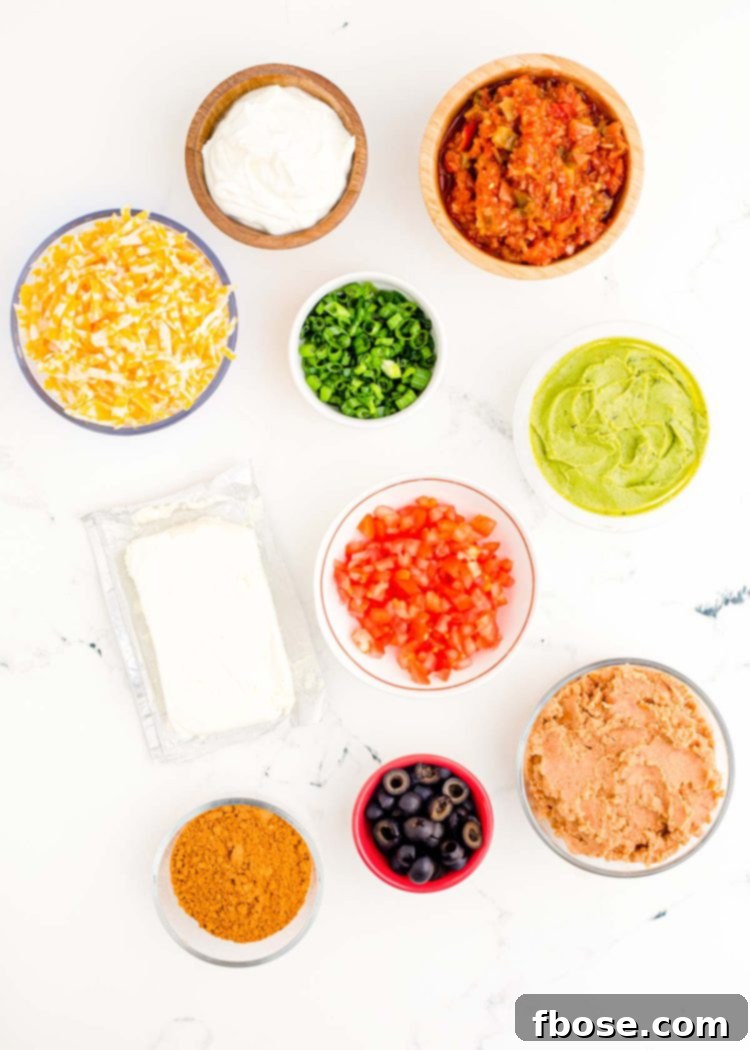 A selection of fresh ingredients including avocados, tomatoes, cheese, and salsa, arranged on a white marble surface, ready for making 7 Layer Dip.