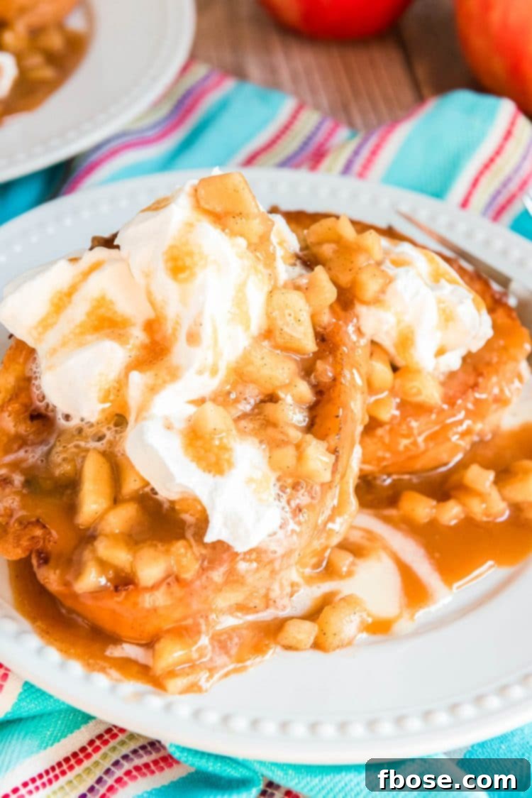French toast stuffed and topped with apples and whipped cream on a white plate.