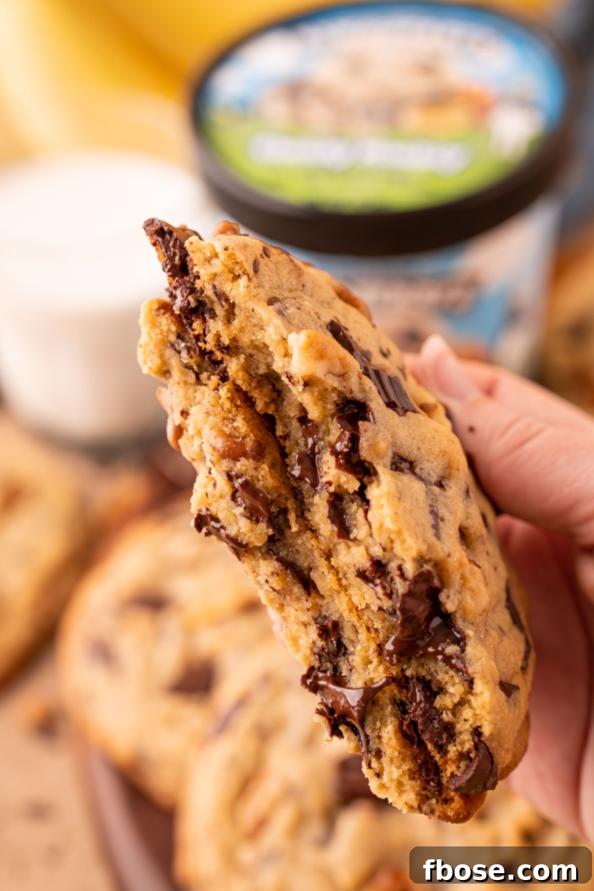 Decadent Chunky Monkey Pudding Cookies 12 A woman's hand holding a broken in half chunky monkey cookies to show the inside texture.