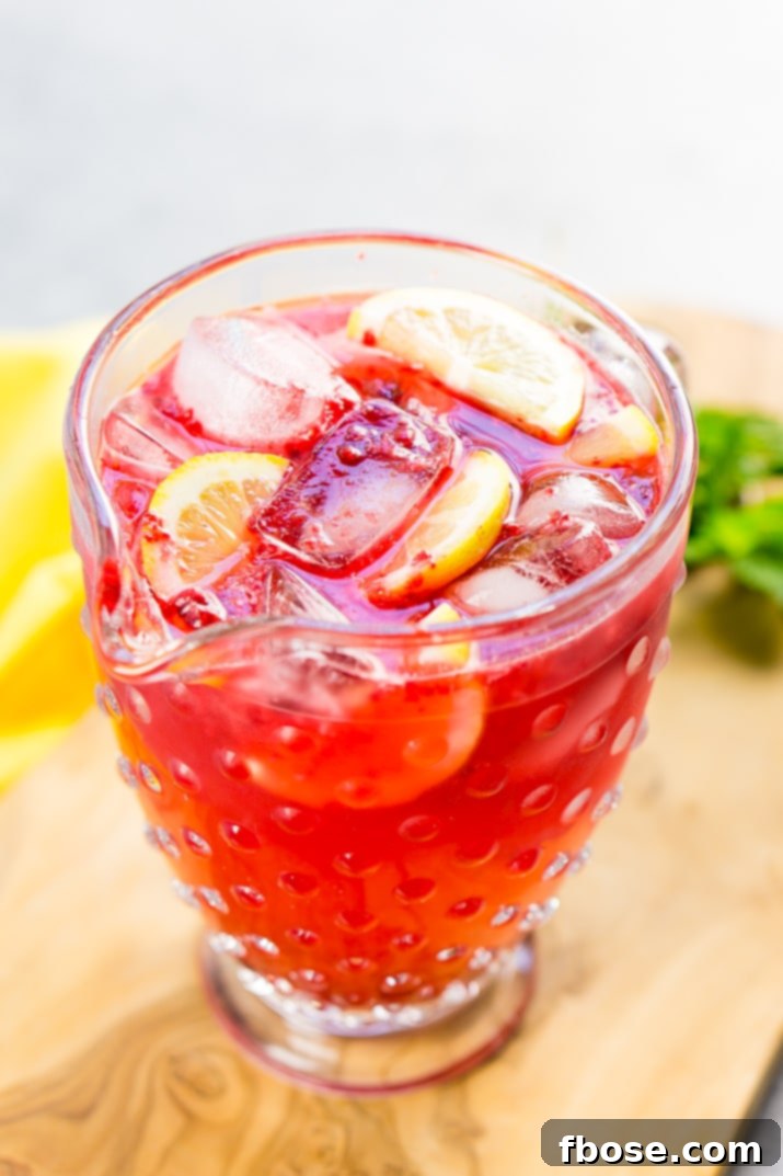 Refreshing Raspberry Lemonade Sparkler 5 Ingredients for Sparkling Raspberry Lemonade laid out: lemons, raspberries, and a bottle of club soda.