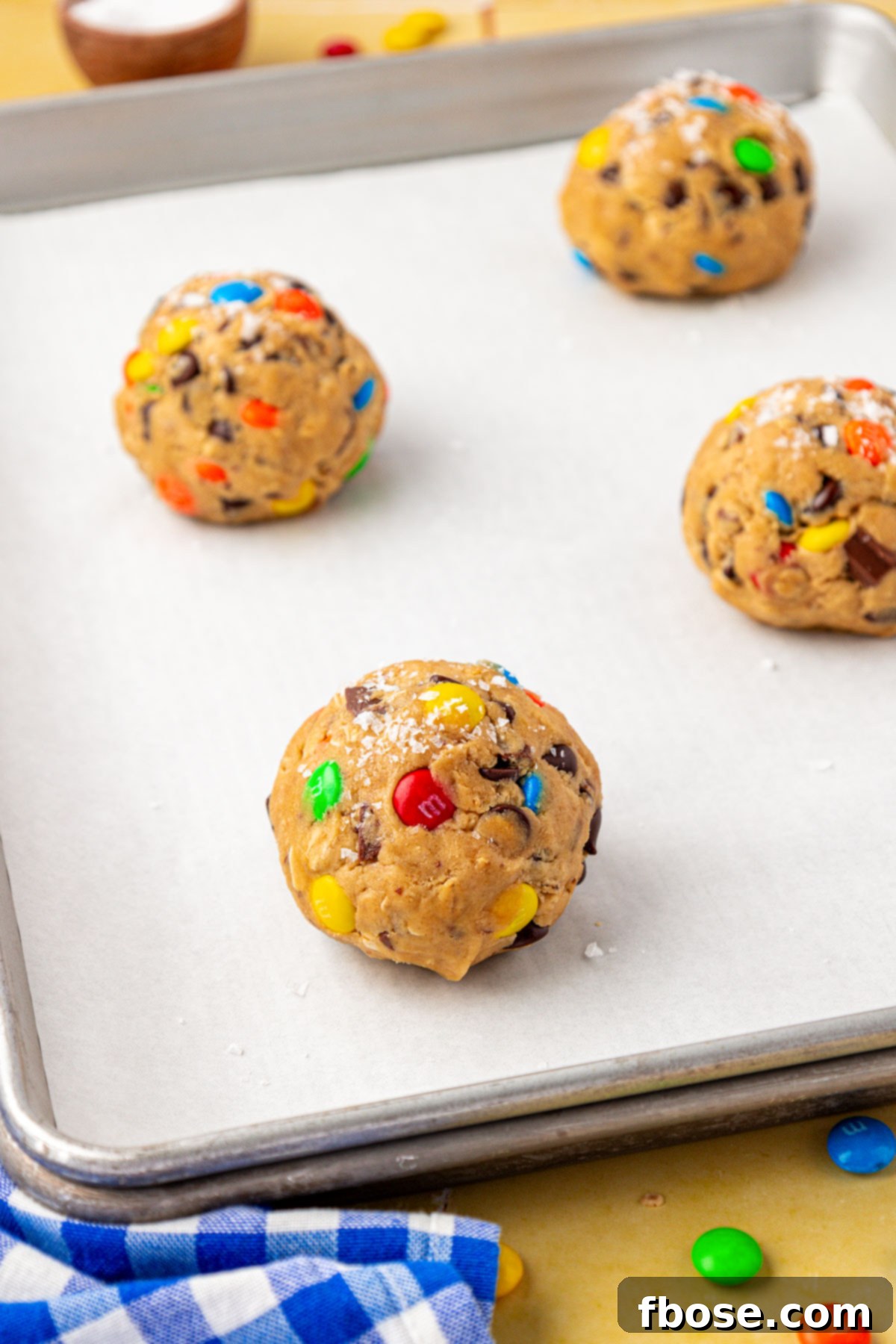 Balls of cookie dough on parchment lined double-stacked baking sheets.