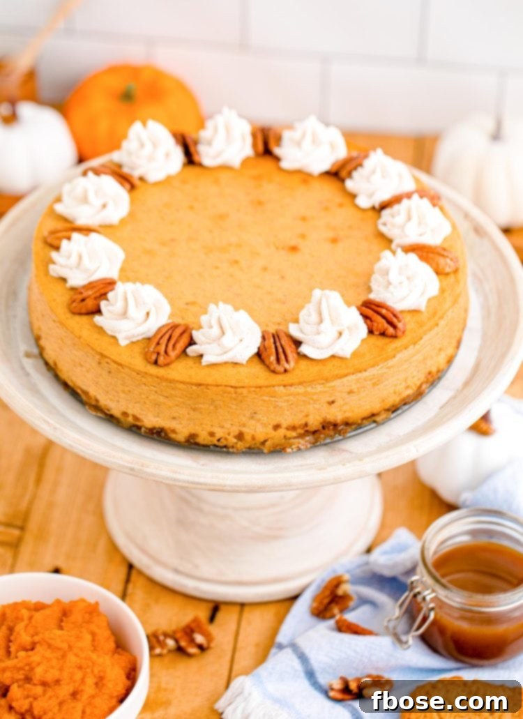 Pumpkin cheesecake on a white cake stand on a wooden table.