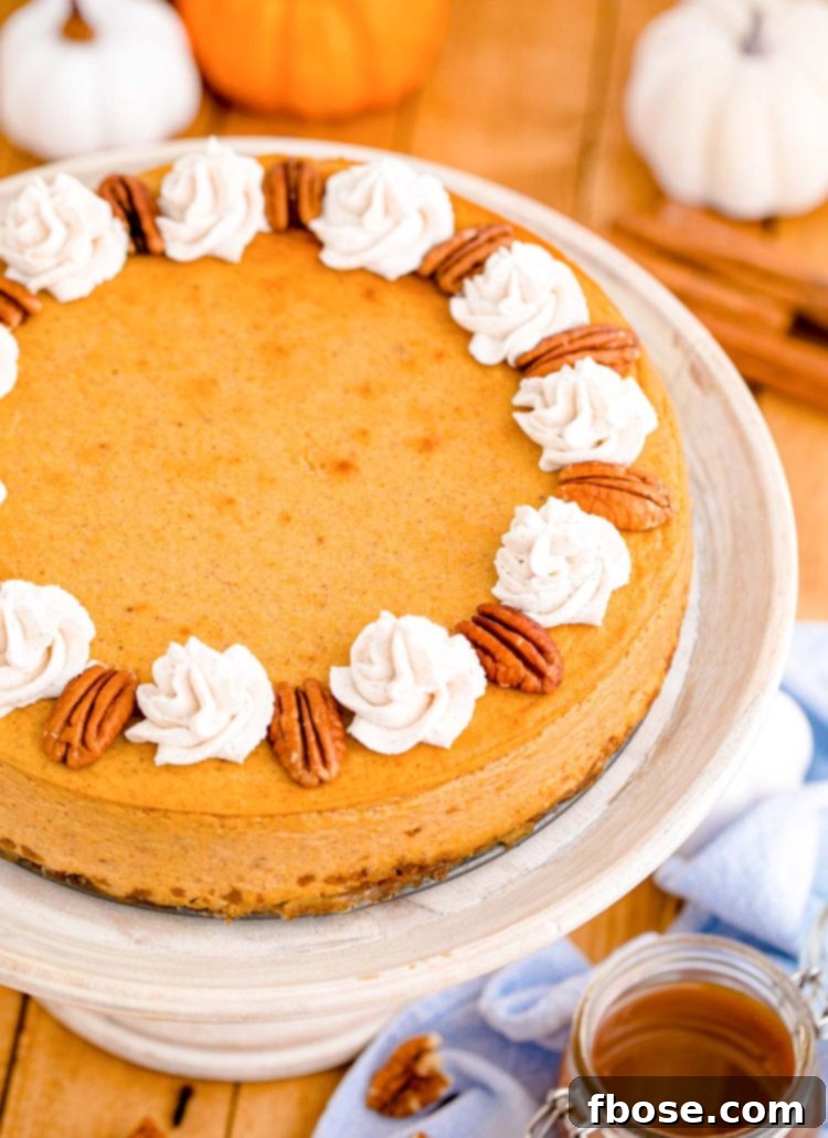 Pumpkin cheesecake on a white cake stand on a wooden table.