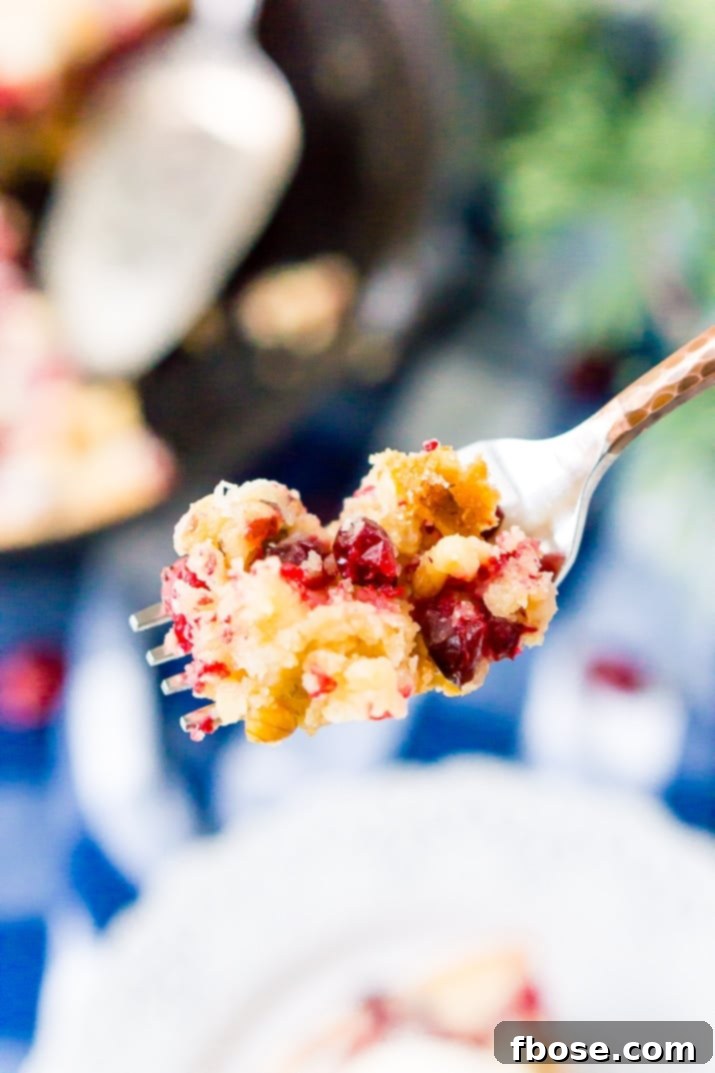 A close-up view of the baked Cranberry Skillet Cake, showing the beautiful golden-brown crust and the juicy, tart cranberries peeking through.
