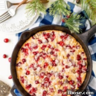A beautifully baked Cranberry Cake, fresh from the skillet, featuring a golden crust and visible cranberries.