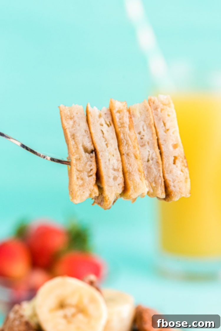 A fork holding a bite-sized stack of fluffy banana pancakes, ready to be enjoyed.