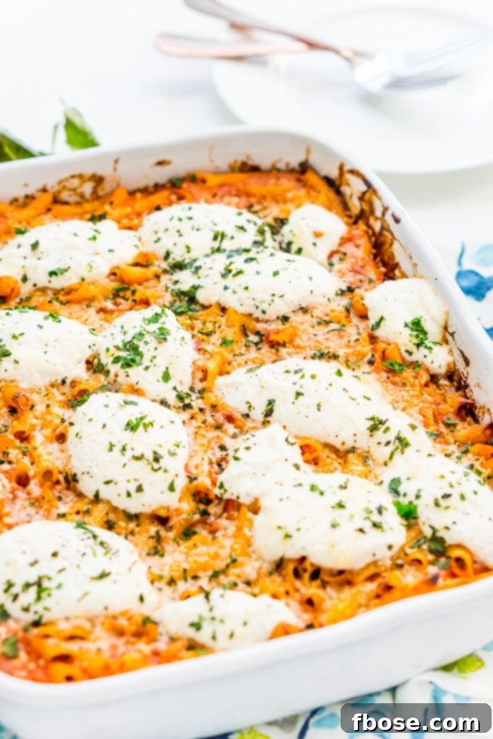 A large baking dish filled with a bubbling, golden-brown Ricotta Pasta Bake, fresh out of the oven, garnished with basil.