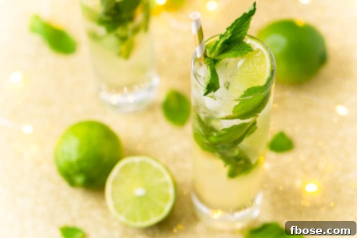 Ingredients for a delicious Mojito recipe, highlighting fresh limes, mint, and a muddler for preparation.