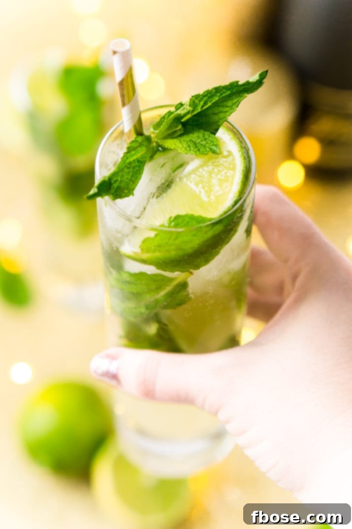 A top-down view of a refreshing Mojito, showcasing the muddled mint, lime, and crushed ice in a highball glass.